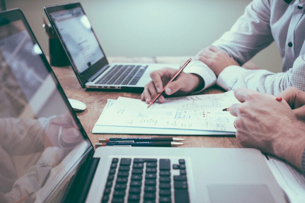 Two people collaborate at a desk with laptops and stationery, discussing a document with notes and diagrams. The clear focus is on accounting principles as they analyze financial data, likely inspired by guidelines from Finn & O'Sullivan.